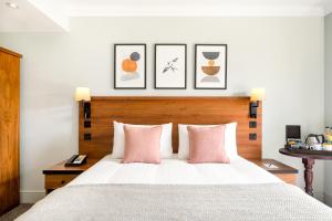 哈斯尔米尔voco Lythe Hill Hotel & Spa, an IHG Hotel的卧室配有一张带粉红色枕头的大床