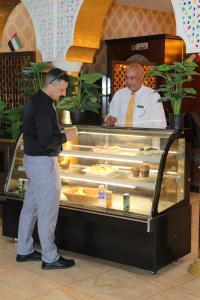 沙迦沙迦国际机场酒店的两个男人站在面包柜台前