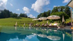 欣特察尔滕凯斯勒穆尔酒店的一个带椅子和遮阳伞的游泳池以及一座小山