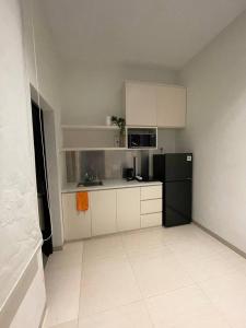 SengkuangMonde Residence H 15 Batam Centre的厨房配有黑冰箱和白色橱柜。