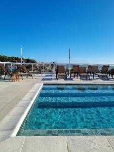 布希奥斯圣托里尼酒店的一个带椅子的游泳池,背景是大海
