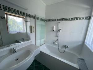 法克湖畔杜罗博拉赫雷斯曼湖滨酒店的白色的浴室设有浴缸和水槽。