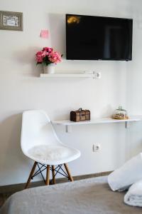 米欧纳Rooms Anna的一间设有白色椅子和墙上电视的房间