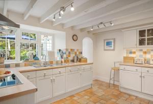 波特里斯The Boy's Cottage的厨房配有白色橱柜、瓷砖地板和窗户。