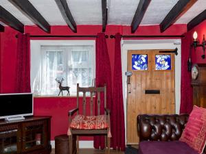 布里奇沃特Pass the Keys Cosy Cottage with Fireplace的一间设有红色墙壁、椅子和窗户的房间