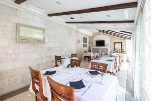 特罗吉尔Heritage Hotel Vila Sikaa的用餐室配有白色的桌子和木椅
