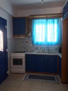 阿波罗Apollon Sunrise的厨房配有蓝色橱柜、水槽和窗户。