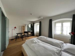 PfaffnauBerghof Erlebnis AG的卧室配有白色的床和桌子