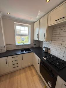 卡迪夫Stylish Penarth Marina Apartment的厨房配有白色橱柜和黑色台面