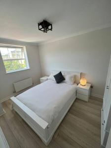 卡迪夫Stylish Penarth Marina Apartment的白色的卧室设有一张大床和一个窗户