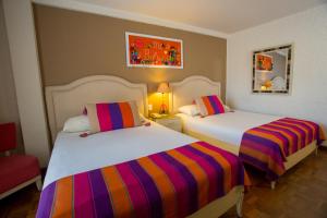 拉巴斯拉巴斯罗萨里奥酒店的一间卧室配有两张带彩色条纹床单的床