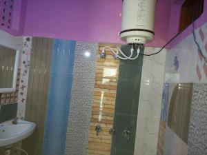 巴德里纳特Badrinath Jb Laxmi hotel的浴室配有水槽和带灯的淋浴