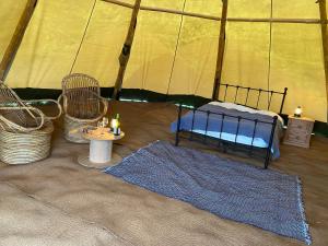 Stoke CanonDevon Tipi Camp And Glamp的帐篷配有1张床、2把椅子和1张桌子