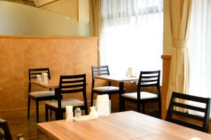 埼玉市Marroad inn omiya的餐厅设有木桌、椅子和窗户