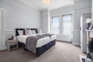 卡斯尔福德The Yorkshire Hosts - Central Castleford 4 Bed House - Free Parking的白色卧室设有一张大床和两个窗户