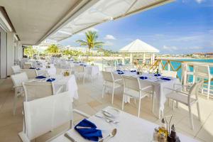 马霍礁圣淘沙集团马霍海滩全包度假村赌场酒店及Spa的一间设有白色桌椅的海洋餐厅