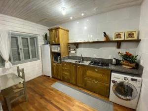 乌鲁比西Chalé Terra Luni的厨房配有木制橱柜、洗衣机和烘干机