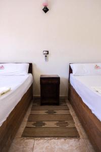 锡瓦Al-Manara Hostel Siwa Oasis的两张位于房间的床,中间有一张小桌子