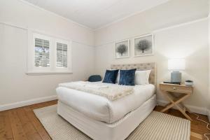奥兰治Sampson Cottage - Historic Charm的白色卧室配有白色大床和蓝色枕头