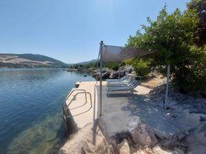 普特尼科维奇Apartments by the sea Zuronja, Peljesac - 13202的坐在湖边的一组长椅