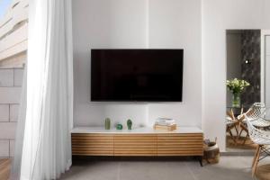埃拉特דירת גן במתחם סי סייד 100 מטר מהים - By Edom的一间客厅,在白色的墙上配有电视