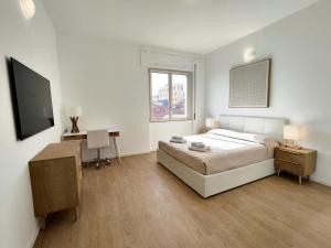奥尔比亚Attico Vespucci Luxury Penthouse的一间卧室配有一张床、一张书桌和一台电视