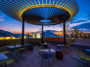 蒙特雷Galeria Plaza Monterrey的黄昏时分带桌椅的屋顶露台
