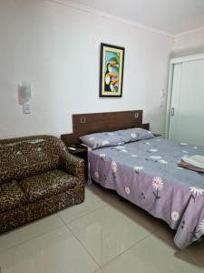 伊瓜苏港Pacurí Hotel的一间卧室配有一张床和一张沙发