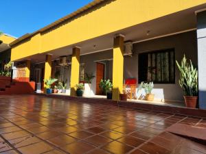伊瓜苏港Pacurí Hotel的黄色建筑,铺着瓷砖地板,种植了盆栽植物