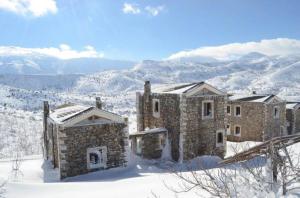 Krousón阿拉达莫斯乡村民宿的一座石头建筑,在雪中,有山地背景