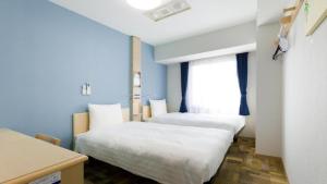 名古屋Toyoko Inn Nagoya-eki Sakuradori-guchi Shinkan的客房设有两张床和窗户。