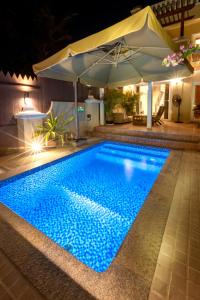 拉斯阿尔卡麦Dar 66 Plunge Pool Resort Townhouses的夜间游泳池,带遮阳伞