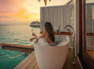 南马累环礁SAii Lagoon Maldives, Curio Collection By Hilton的坐在浴缸里的女人,喝一杯葡萄酒