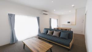 宫古岛BiBi Hotel 宮古空港前 SouthTower的客厅配有蓝色的沙发和桌子