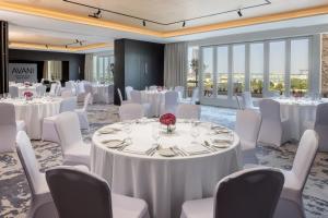 迪拜Avani Plus Palm View Dubai Hotel & Suites的宴会厅配有白色的桌子和白色的椅子