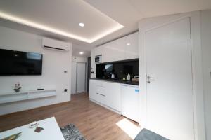 萨拉热窝Luxury Apartments Una Sarajevo的厨房配有白色橱柜和平面电视。