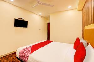艾哈迈达巴德Hotel Alexa的一间卧室配有一张带红色枕头的床和一台电视。