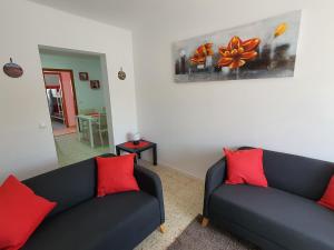 特吉塞Casa El Eco del Volcán 1的客厅配有2张黑色沙发和红色枕头