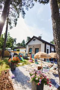 GdówRABA RESORT - Domki i Apartamenty pod Krakowem的一个带椅子和遮阳伞的庭院和一座房子