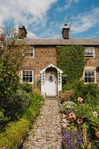 贝克韦尔Swallow Cottage, Bakewell的砖屋,有白色的门和一些花