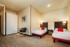 博洛尼亚JR Hotels Bologna Amadeus的一间设有两张床、一张桌子和一把椅子的房间