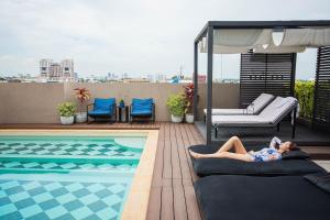 曼谷THEA Serviced Apartment by TH District, SHA Extra Plus的躺在游泳池旁床边的女人