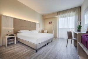 雷诺河畔卡尔代拉拉JR Hotels Gate 7 Bologna的卧室配有一张白色大床和一张书桌