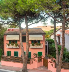 坎普码头Hotel Elba的粉红色的建筑,有绿色百叶窗和树木