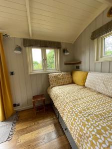 TodberBathsheba, Luxurious Shepherds Hut set in Todber a hamlet set in Thomas Hardy's iconic rural Dorset的一间小卧室,配有床和2个窗户