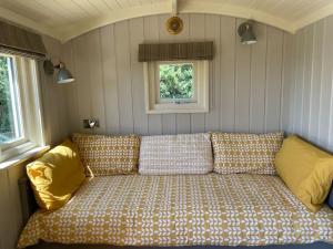 TodberBathsheba, Luxurious Shepherds Hut set in Todber a hamlet set in Thomas Hardy's iconic rural Dorset的一张沙发,位于带两个窗户的房间的角落