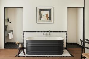 鹿特丹Morgan & Mees Rotterdam的浴室铺有黑色和白色瓷砖,配有浴缸。