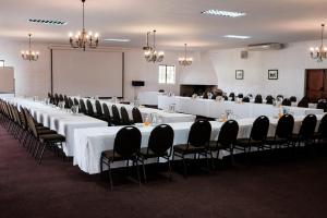 波特里弗Houw Hoek Hotel的一间会议室,配有白色的桌子和黑色的椅子