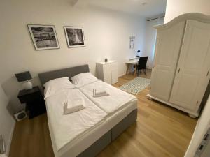纽伦堡Swan Rooms的一间卧室配有一张带白色床单的床和一张书桌。