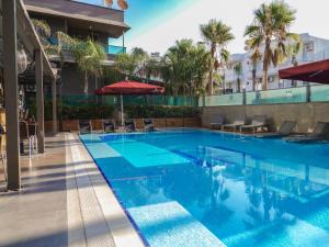 安塔利亚拉仁家庭Spa酒店 - 精品级的一座带椅子和遮阳伞的游泳池位于一座建筑旁边